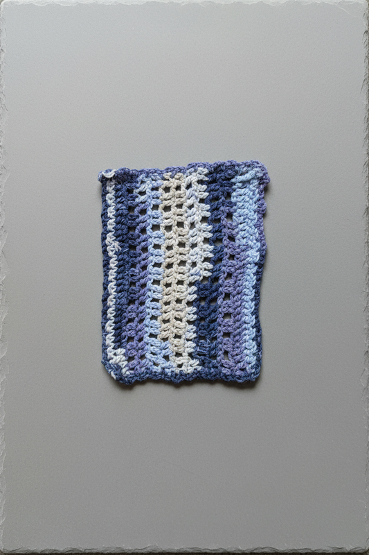 Crocheted fabric with blue and white stripes on a gray background
